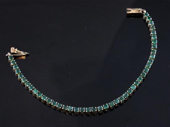 A 14ct gold and emerald line bracelet, 7in.